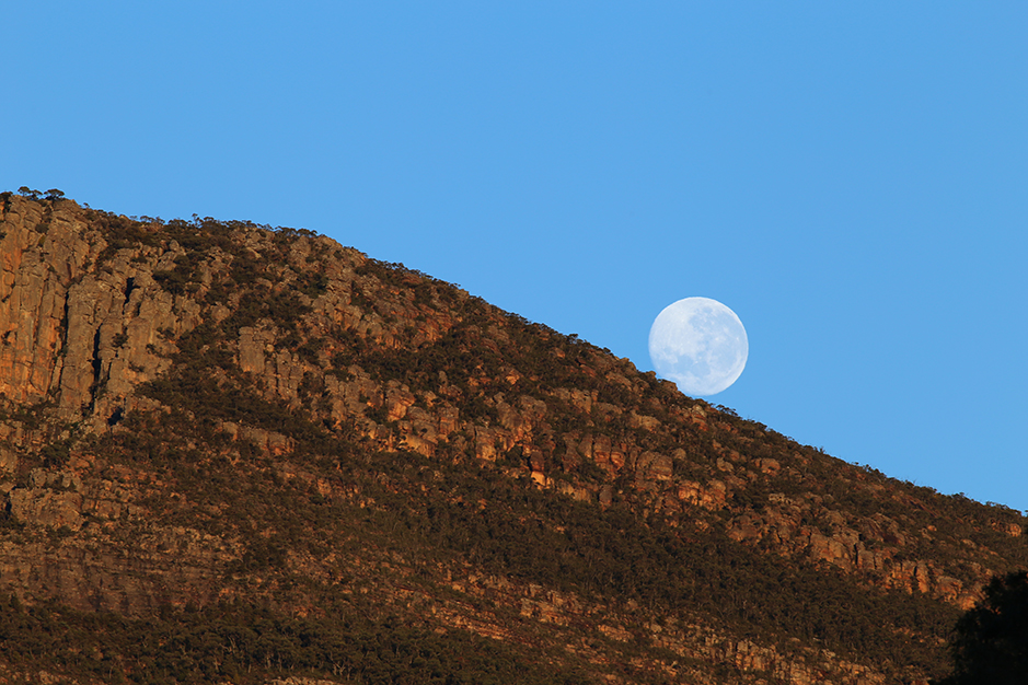 From Grampians Paradise Camping and Caravan Parkland the moon sets behind Redman Bluff as the rising sun turns the cliffs red on the 7th July 2020